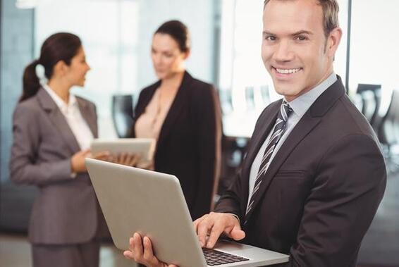Man in office setting with laptop smiling